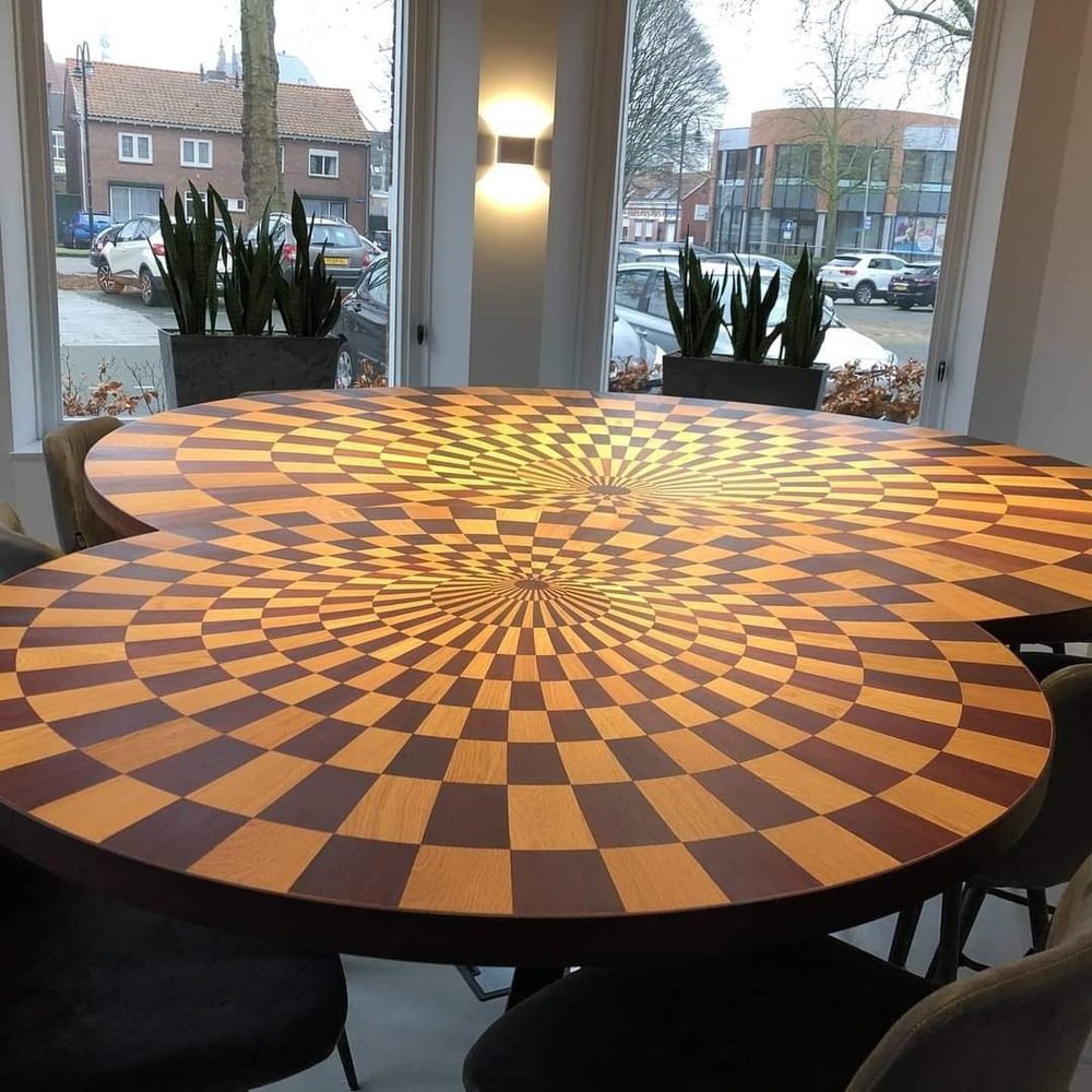Ronde kunsttafel met radiaal houtinlegpatroon in meerdere houtsoorten